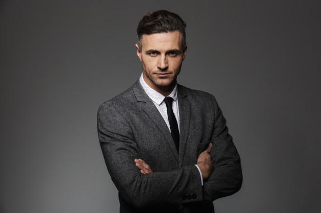 portrait-of-masculine-man-wearing-business-suit-posing-with-serious-look-keeping-arms-folded-isolated-over-gray-wall_171337-32727.jpg